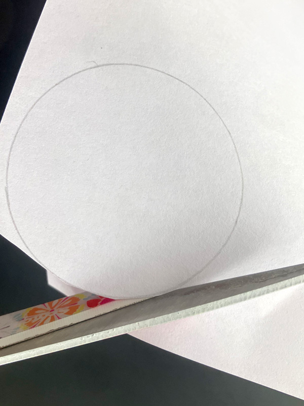 Scissors cutting a penciled circle from paper