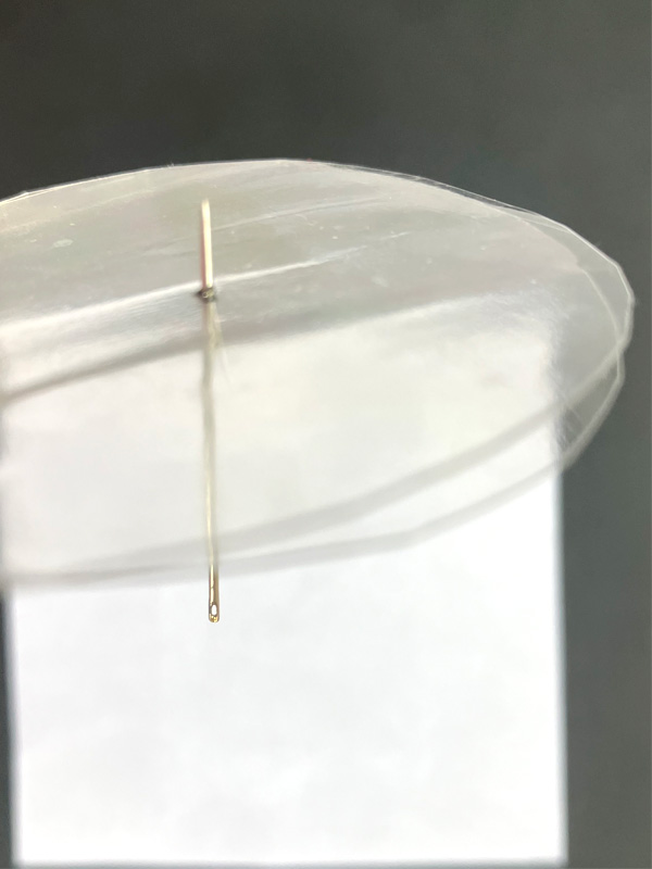 Liquid dripping from toothpick through plastic lid
