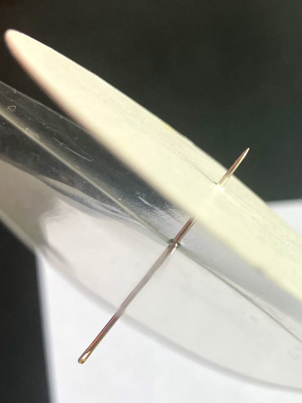 Two needles piercing clear plastic surface
