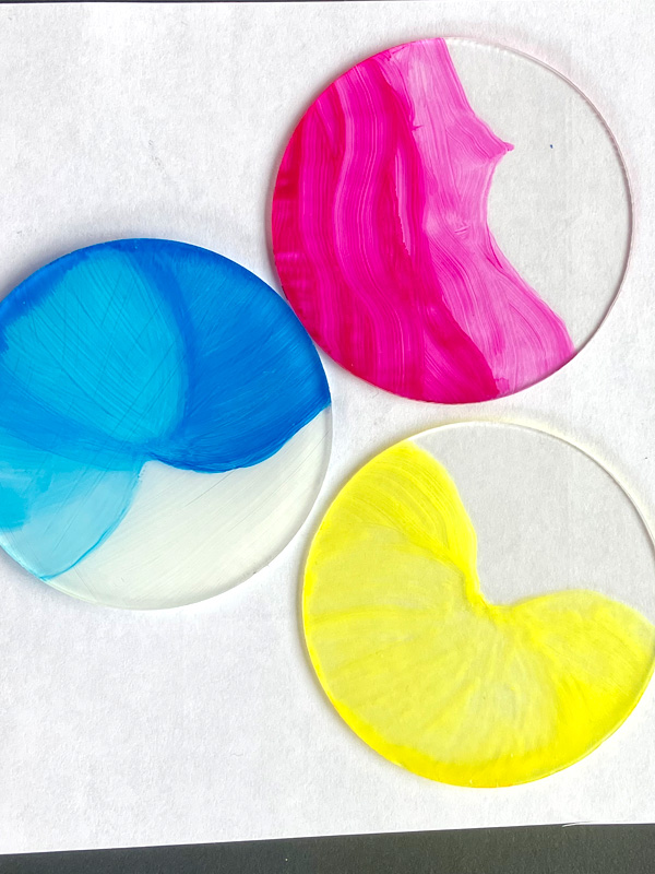 Three colourful abstract resin discs on white background